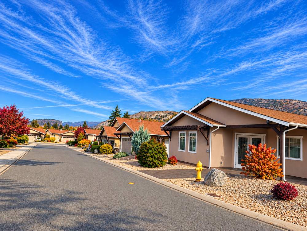 Stucco home with French doors, a paver patio, a large boulder and a yellow fire hydrant on a street at Canyon Desert Golf Villas