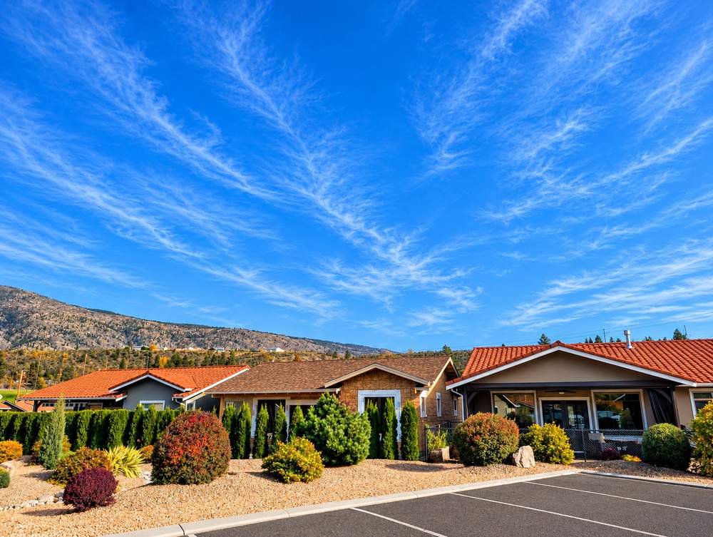 Single-storey stucco homes with tile roofs and gravel landscaping beside a parking area at Canyon Desert Golf Villas