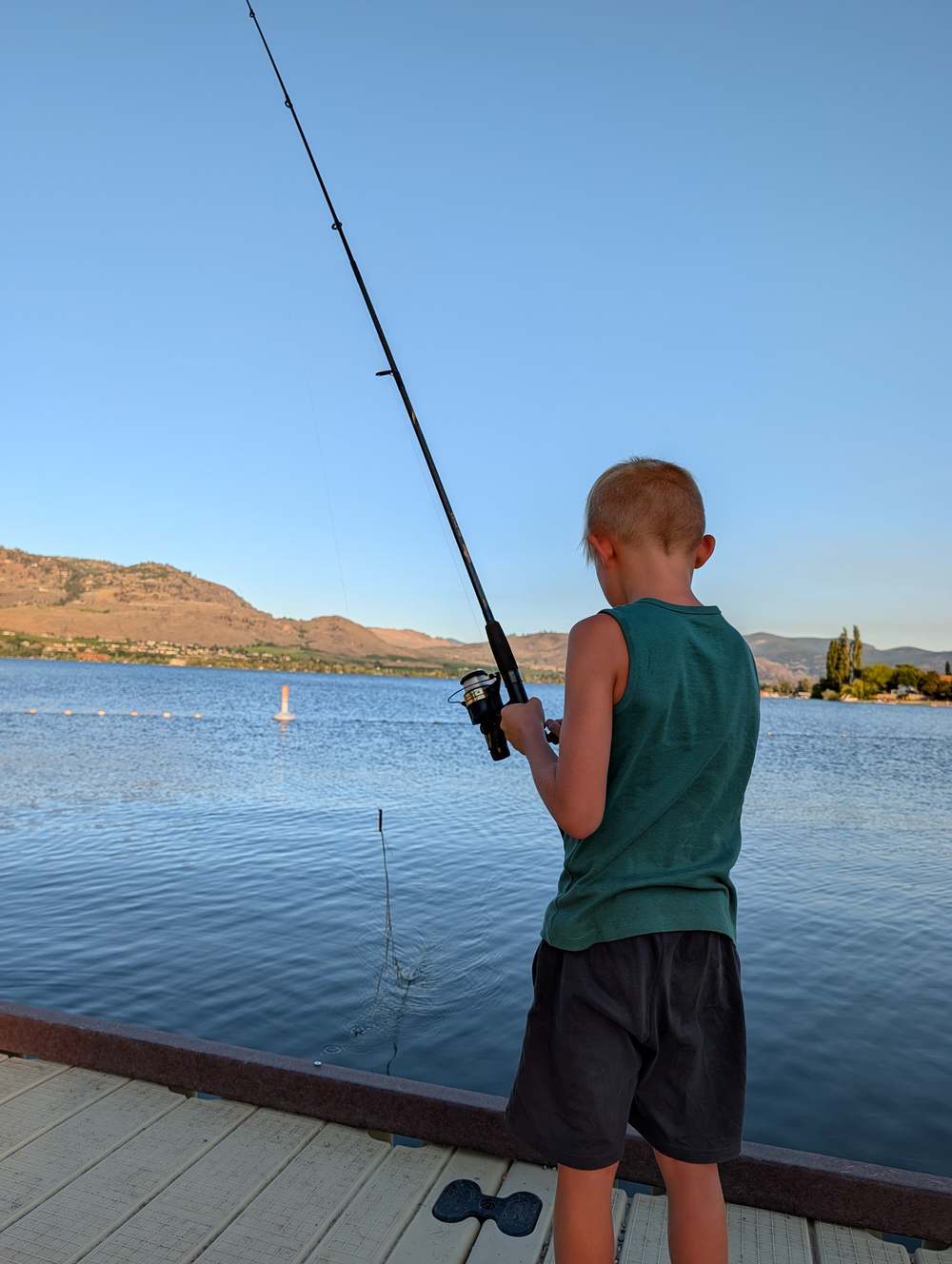 A child fishing off a dock on Osoyoos Lake at sunset